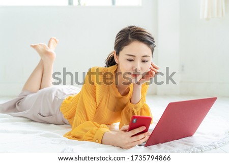 Attractive asian woman using a laptop PC and a smart phone.