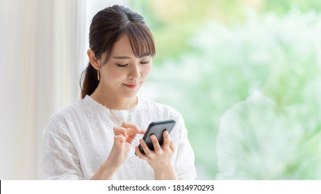 Attractive Asian Woman Using Smart Phone At Home