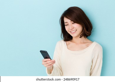 Attractive Asian Woman Using Smart Phone Isolated On Blue Background