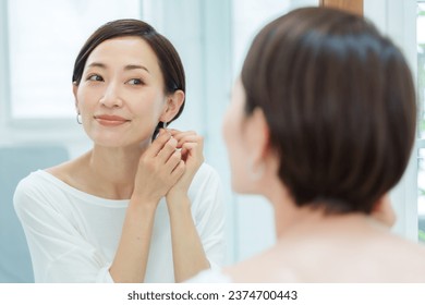 attractive asian woman wearing earrings in bathroom - Powered by Shutterstock