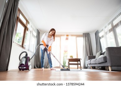 Attractive Asian Woman In White Shirt Is Using Vacuum Cleaner On The Rug Or Carpet And Floor. Cleaning House.