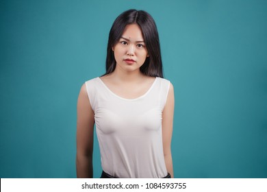 Attractive Asian Woman In White Transparent Top Looking At Camera Isolated On Blue Background