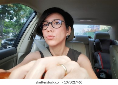 Attractive Asian Working Woman Driving A Car In Traffic Jam. Driving Safety Concept, Working Mom Lifestyle, City Life.