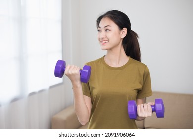 Attractive Asian Young Fitness Woman Lifting Dumbbell Weights Workout At Home In Living Room. Fresh Feeling Female Training And Exercise Wearing Sport Wear Fit Body.