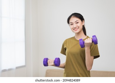 Attractive Asian Young Fitness Woman Lifting Dumbbell Weights Workout At Home In Living Room. Fresh Feeling Female Training And Exercise Wearing Sport Wear Fit Body.