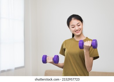 Attractive Asian Young Fitness Woman Lifting Dumbbell Weights Workout At Home In Living Room. Fresh Feeling Female Training And Exercise Wearing Sport Wear Fit Body.