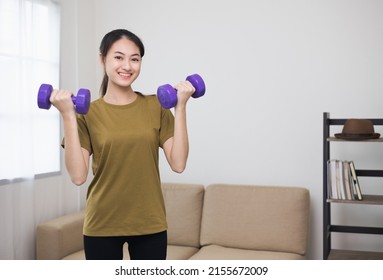 Attractive Asian Young Fitness Woman Lifting Dumbbell Weights Workout At Home In Living Room. Fresh Feeling Female Training And Exercise Wearing Sport Wear Fit Body.