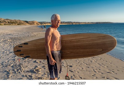 Attractive Australian Mature Man Surfer With Cool Vintage Surfboard On Beach At Sunset. Senior Adult Happy To Be Back To Surf . Outdoors Sports Adventure, Active Older People And Retirement Lifestyle.