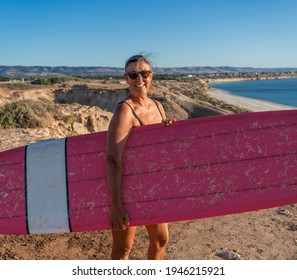 Attractive Australian Mature Surfer With Cool Vintage Surfboard At Sunset. Fit Woman In Her 50s Happy To Be Back To Surf . Outdoors Sports Adventure, Active Older People And Retirement Lifestyle.