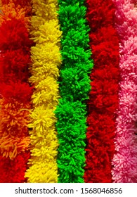 An attractive backround of multicolred string of pom poms aranged side by side - wool craft
