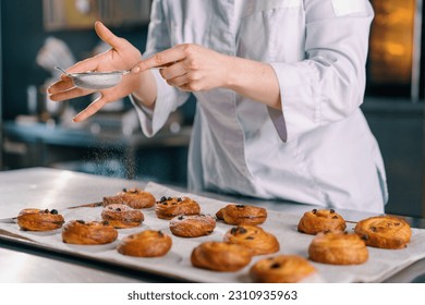 attractive baker sprinkles powdered sugar ready freshly baked hot fragrant buns baking production bakery - Powered by Shutterstock