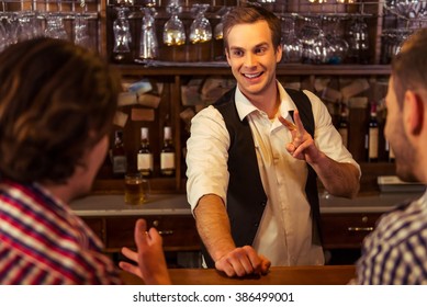 Attractive bartender is smiling and taking order of two men sitting at bar counter in pub - Powered by Shutterstock