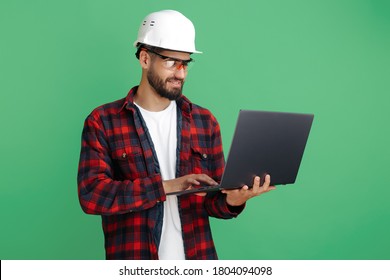 Attractive Bearded Engineer Or Constructor Man In Casual Outfit With Computer Over Green Background.