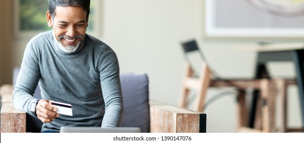 Attractive Bearded Hipster Asian Father Or Hispanic Old Man Using Laptop And Credit Card Payment Shopping Online With Customer Network Connection Via Omni Channel System. Older Man With Technology.