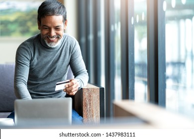 Attractive bearded hipster asian father or Hispanic old man using Laptop and credit card payment shopping online with customer network connection via omni channel system. Older man with technology. - Powered by Shutterstock