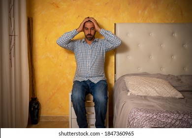 Attractive Bearded Man Depressed And Upset In The Bedroom At Home. Dramatic 30-40 Year Old Lifestyle Portrait, Handsome Man Sitting On Bed, Worried And Desperate. Depression Concept