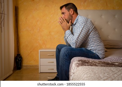 Attractive Bearded Man Depressed And Upset In The Bedroom At Home. Dramatic 30-40 Year Old Lifestyle Portrait, Handsome Man Sitting On Bed, Worried And Desperate. Depression Concept