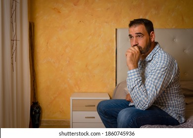 Attractive Bearded Man Depressed And Upset In The Bedroom At Home. Dramatic 30-40 Year Old Lifestyle Portrait, Handsome Man Sitting On Bed, Worried And Desperate. Depression Concept