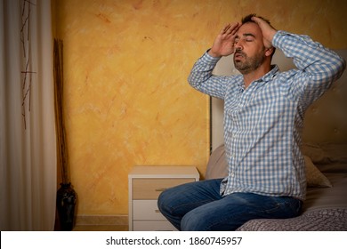 Attractive Bearded Man Depressed And Upset In The Bedroom At Home. Dramatic 30-40 Year Old Lifestyle Portrait, Handsome Man Sitting On Bed, Worried And Desperate. Depression Concept