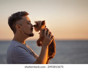 Attractive bearded man kissing his yorkshire terrier. Dog care and love concept. - Powered by Shutterstock