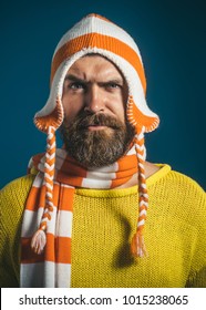 Attractive Bearded Man In Warm Knitted Hat And Scarf. Surprised Handsome Man Wearing Winter Funny Hat And Scarf. Handsome Man With Beard Wearing Sweater, Hat And Scarf. Autumn-winter Fashion. Closeup.