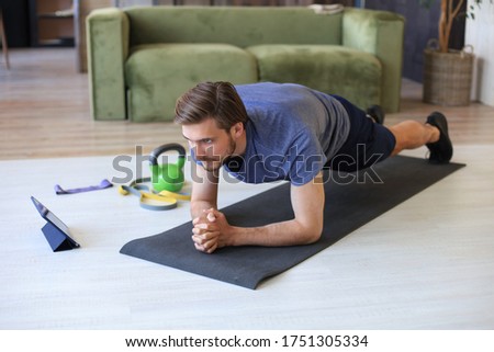 Attractive beared man doing plank exercise at home during quarantine. Fitness is the key to health.