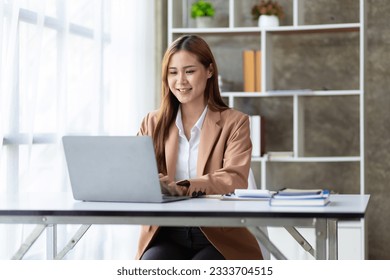 Attractive beautiful Asian business woman working on laptop on desk in office.