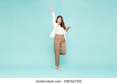 Attractive beautiful Asian businesswoman standing and hands up raised arms from happiness and holding calculator isolated on green background, Excited woman winner success concept - Shutterstock ID 1987667105