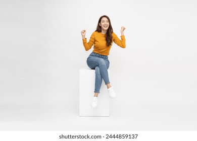 Attractive beautiful Asian female sitting on white wood box and hands up raised arms from happiness, Excited woman winner success concept - Powered by Shutterstock