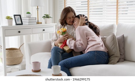 Attractive Beautiful Asian Middle Age Mum Sit With Grown Up Daughter Give Gift Box And Flower In Family Moment Celebrate Mother Day. Overjoy Bonding Cheerful Kid Embrace Relationship With Retired Mom.