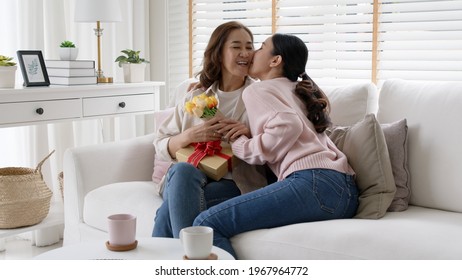 Attractive Beautiful Asian Middle Age Mum Sit With Grown Up Daughter Give Gift Box And Flower In Family Moment Celebrate Mother Day. Overjoy Bonding Cheerful Kid Embrace Relationship With Retired Mom.