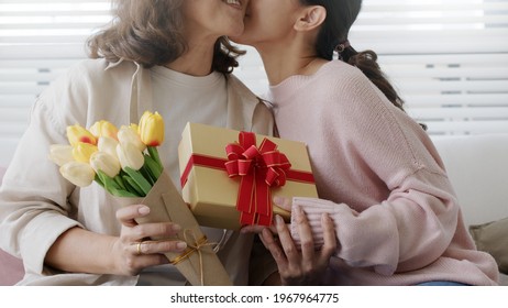 Attractive Beautiful Asian Middle Age Mum Sit With Grown Up Daughter Give Gift Box And Flower In Family Moment Celebrate Mother Day. Overjoy Bonding Cheerful Kid Embrace Relationship With Retired Mom.