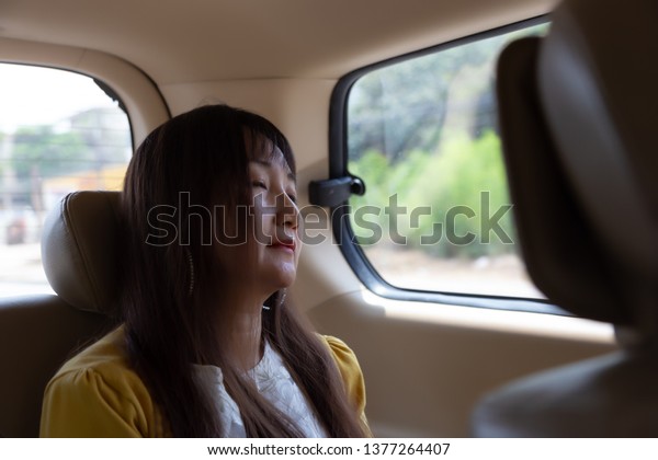 Attractive beautiful asian woman feels sleepy and\
tired during traveling to long distance and crossing to other\
country by van. She is going back home for visit her family in long\
weekend holiday