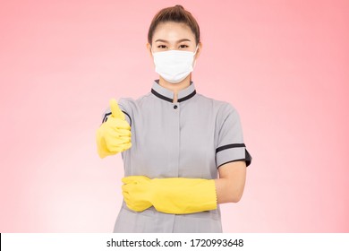 Attractive Beautiful Asian Woman Maid Wearing Face Mask And Gloves Smile And Thumbs Up Sign Feeling So Happiness And Confident,Isolated On Pink Background,Cleaning Service Concept