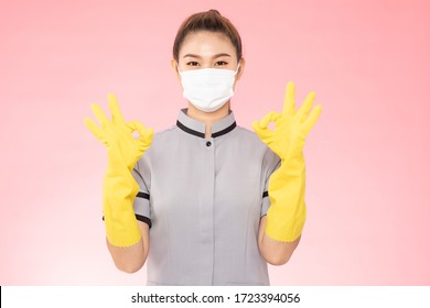 Attractive Beautiful Asian Woman Maid Wearing Face Mask And Gloves Smile And Okay Sign Feeling So Happiness And Confident,Isolated On Pink Background,Cleaning Service Concept