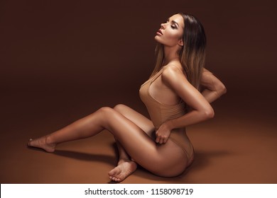 Attractive Beautiful Brunette Woman With Ideal Tan Body In Sensual Pose. Girl In Glamour Makeup.