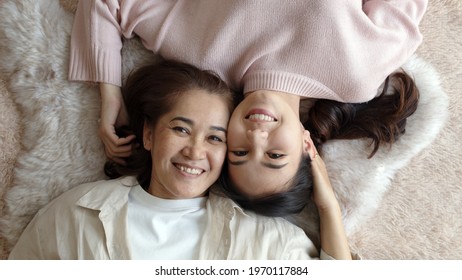 Attractive beautiful cheerful authentic real family two people laying down look at camera above tender emotion hug kiss cuddle relax comfort sleep in living room in health care healthy mother day.