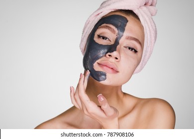 an attractive beautiful girl with a pink towel on her head applied a clay mask