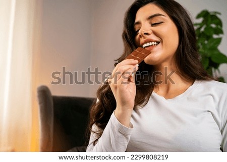 Attractive beautiful long hair girl eating bar of chocolate 