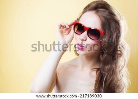 Attractive beautiful surprised young woman in sunglasses on gold back