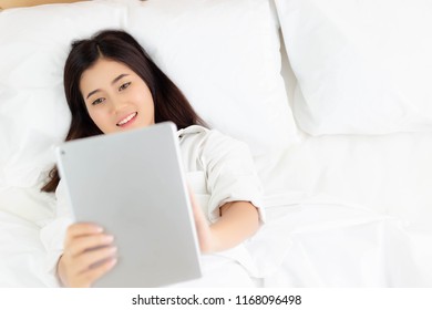 Attractive Beautiful Woman Use Tablet For Communicating With Friends, Family On Bed. Charming Beautiful Young Woman Is Enjoying And Satisfying High Speed Internet By Broadband Internet. Copy Space