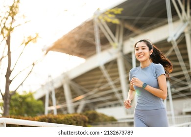 Attractive beautiful woman wearing sportswear running at sport stadium. Fit woman jogging outdoor. Workout exercise in the morning. Healthy and active lifestyle concept.