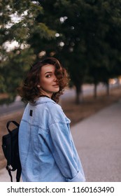 Attractive Beauty Woman Walking On The Street While Wearing Blue Jeans. Photo From Back And Girl Is Turn Around.