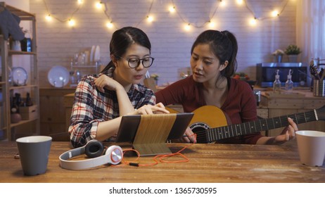 Attractive Best Friend Woman Touching Digital Pad Discussing With Sister While Practicing Guitar And Singing. Young Girls Use Tablet For Showing Lyrics To Roommate Writing Song Together Night Kitchen