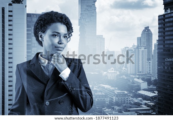 Attractive black African\
American business woman in suit with hand on chin thinking how to\
succeed, new career opportunities, MBA. Bangkok on background.\
Double exposure.