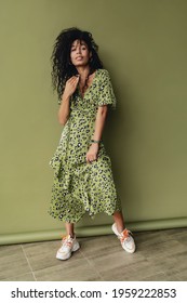 Attractive Black African American Woman Posing In Stylish Green Leopard Printed Dress Isolated On Green Studio Background, Summer Fashion Trend, Happy Smiling Curly Hair