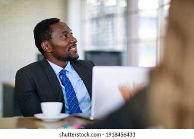 Attractive Black Businessman Sitting And Concentrated Listening To Presentation In A Multiracial Business Meeting.