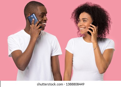 Attractive Black Couple In White T-shirts Holding Gadgets Talking On Mobile Phones, Looking At Each Other Smiling, Isolate On Pink Blank, Communication Connection, Dating Flirting, Modern Tech Concept