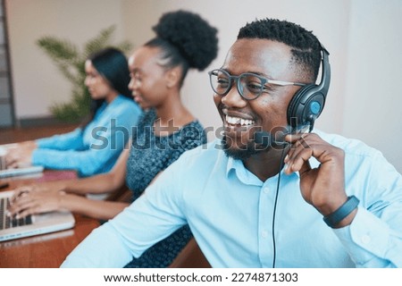 An attractive Black man speaks to client on headset remote call, smiling