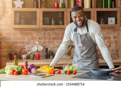 Attractive Black Positive Man Posing At Kitchen While Cooking Dinner For His Family, Free Space